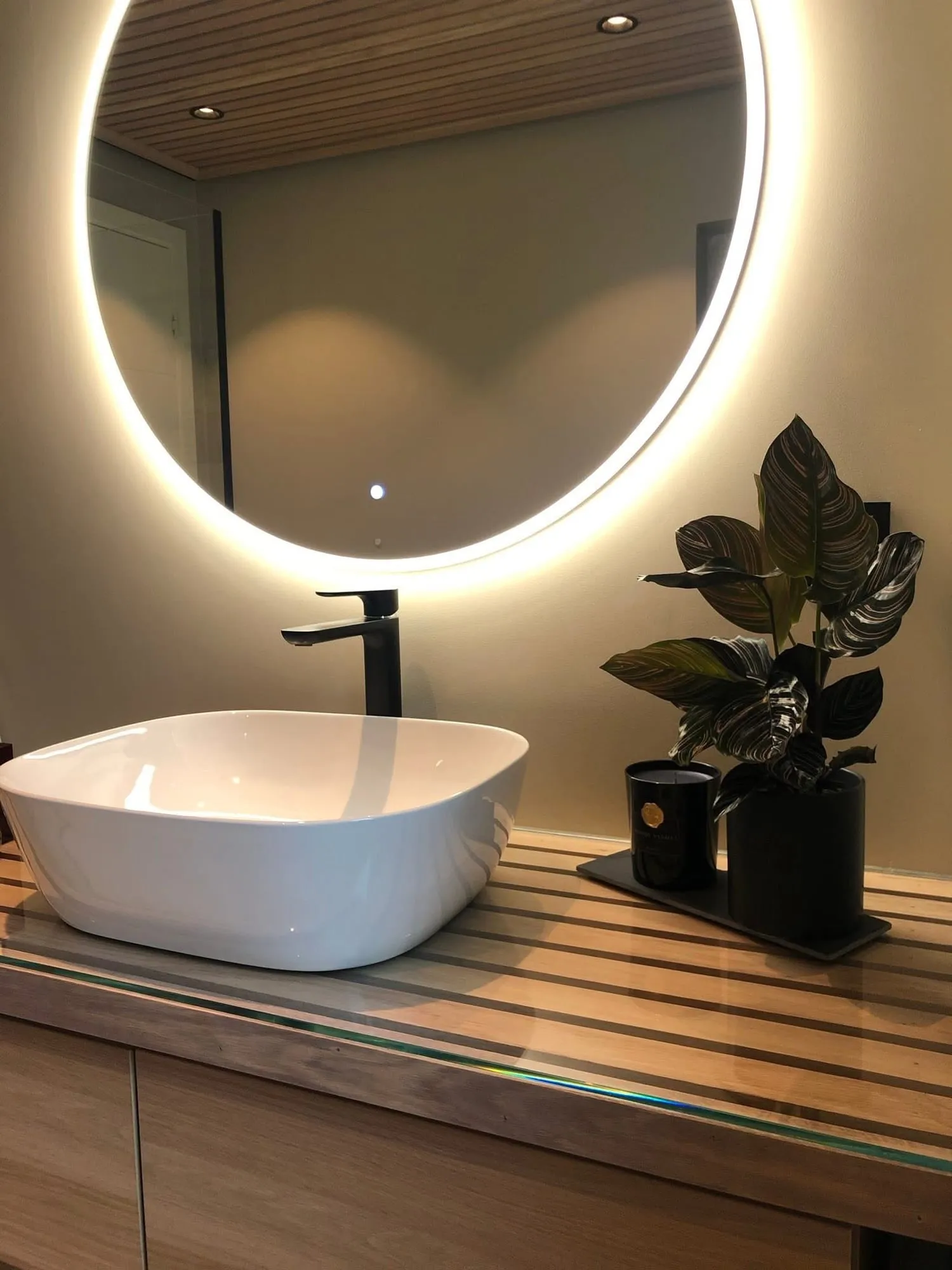Baderomsinnredning med eikeplate under glass og rundt speil med lys
