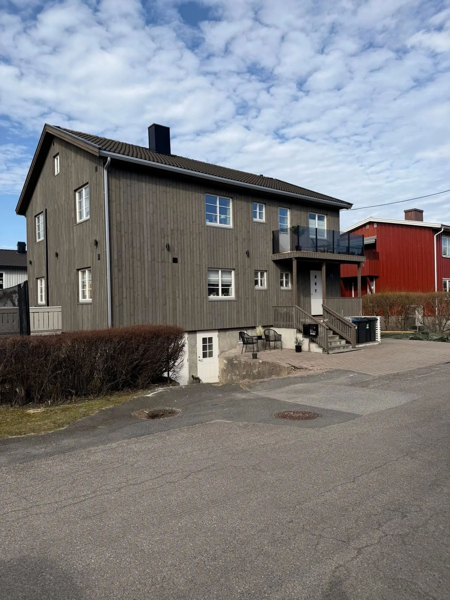 Huset med ny stående trekledning og veranda med glassrekkverk