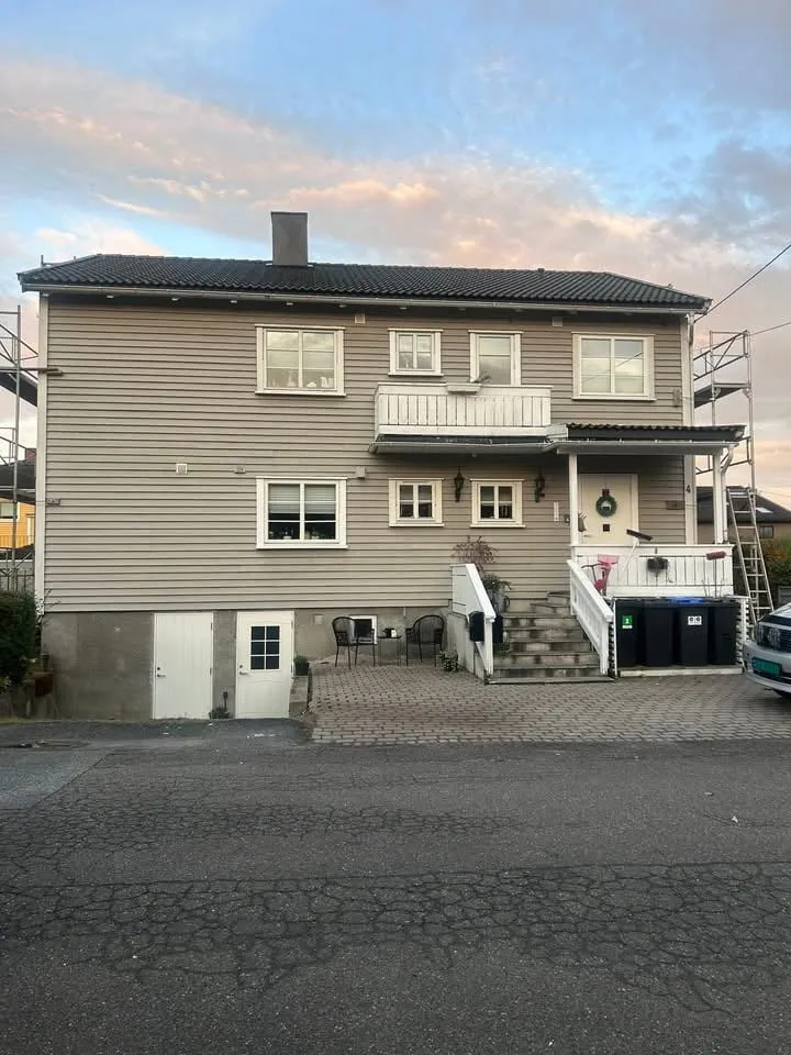 Huset før, med gammel liggende kledning og hvit balkong