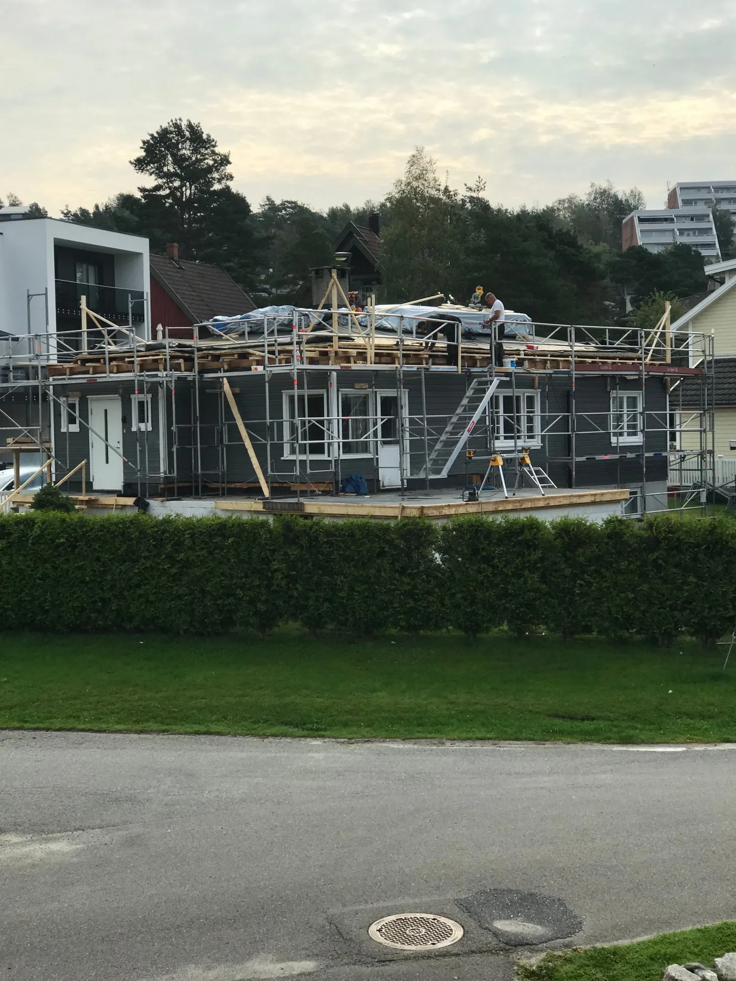 Huset i én etasje med stillas og overdekket tak før påbygget